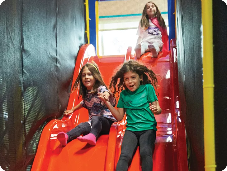three girls going down a slide